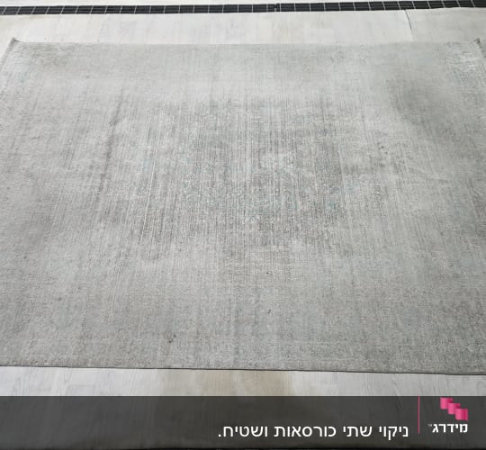 שטיח אפור על רצפה, סימני לכלוך נראים בבירור